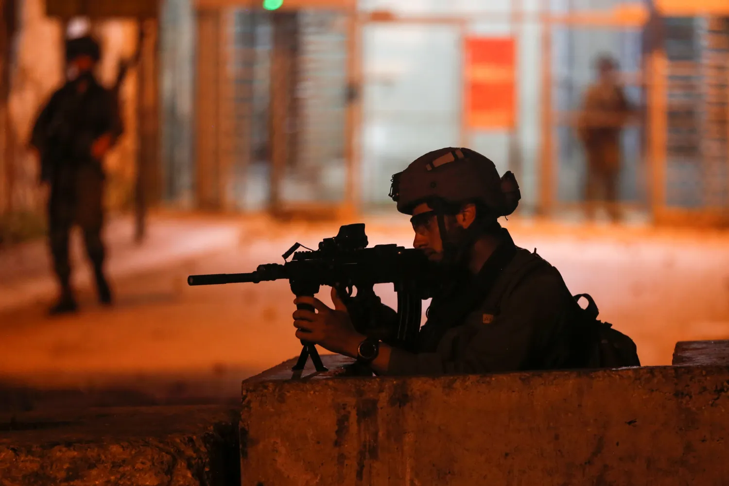 A member of Israeli forces aims his weapon as Palestinians take part in an anti-Israel protest over tension in Jerusalem, in Hebron in the Israeli-occupied West Bank April 24, 2021. REUTERS/Mussa Qawasma


