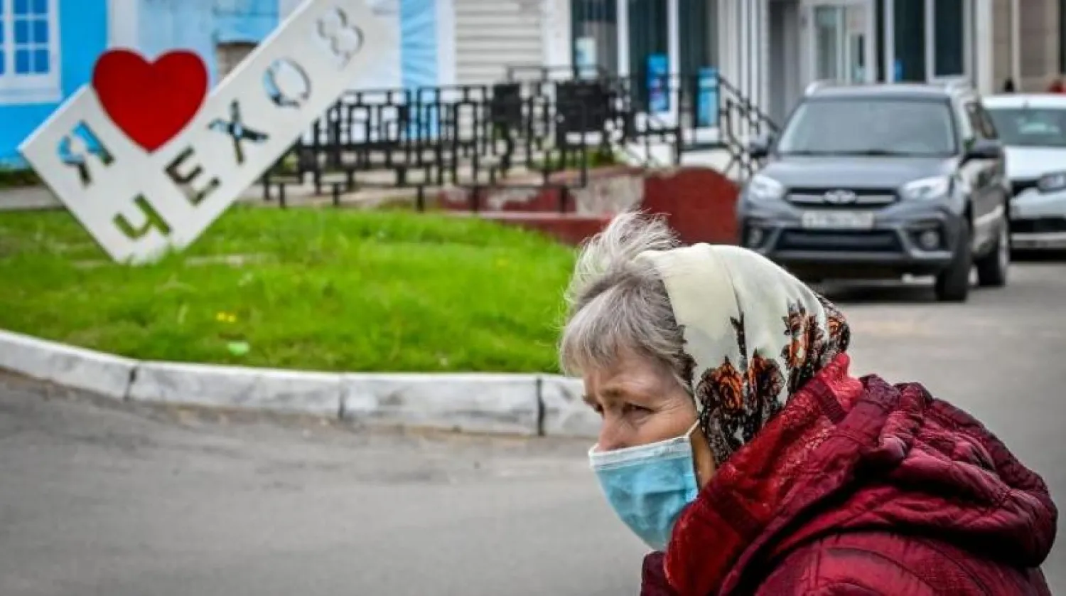 Moskova'nın dışındaki Çehov kasabasında yüz maskesi takan bir kadın caddeden karşıya geçiyor (AFP)