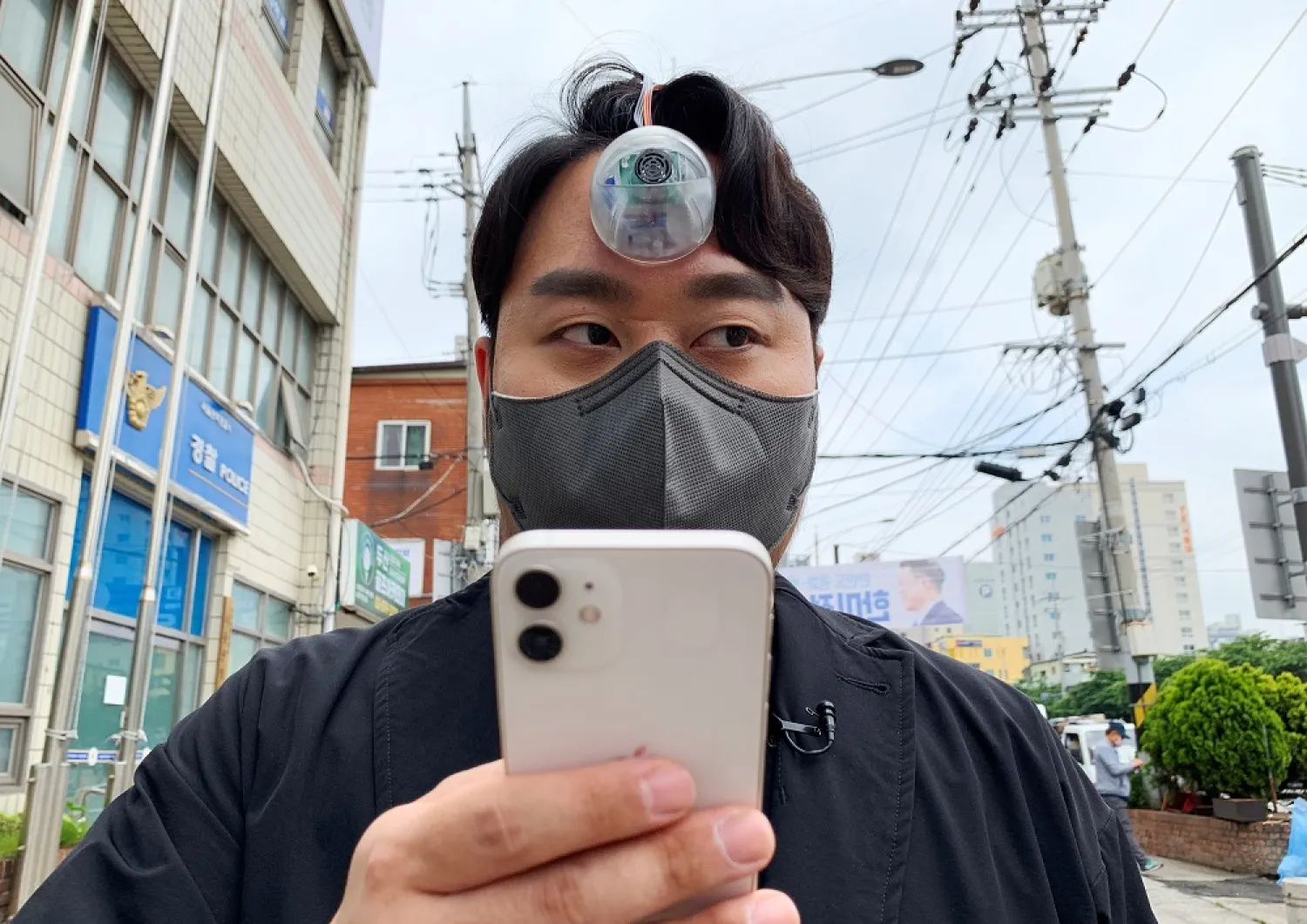 South Korean industrial designer Paeng Min-wook showcases a robotic eye, called “The Third Eye”, on his forehead as he uses his mobile phone while walking on street, in Seoul, South Korea, March 31, 2021. (Reuters)