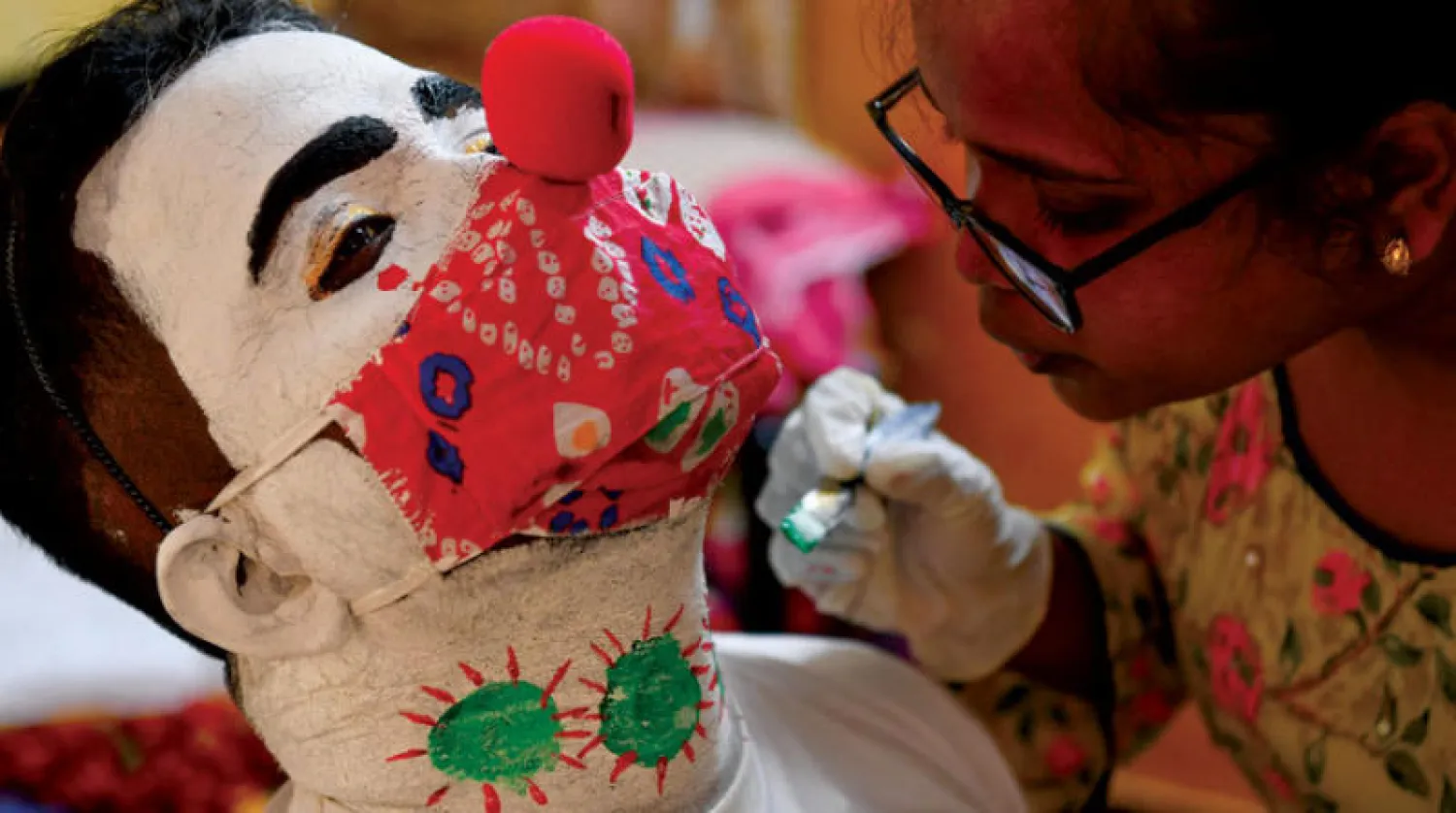 شقيقة أشوك كورمي ترسم وجهه قبل ذهابه إلى الأحياء الفقيرة (أ.ف.ب)