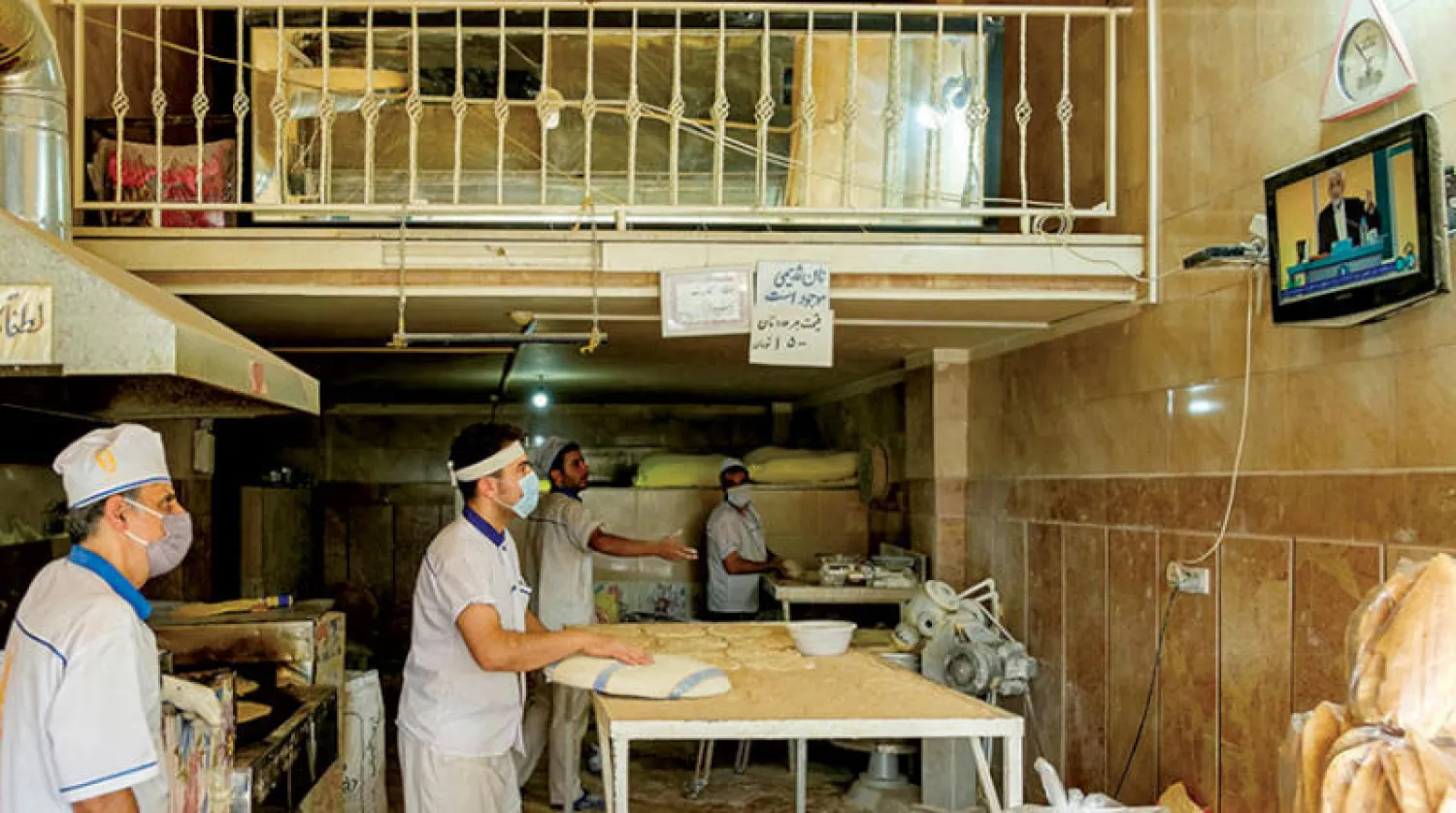 عاملون في مخبز يتابعون المناظرة الاقتصادية بين مرشحي الرئاسة الإيرانية أول من أمس (التلفزيون الإيراني)