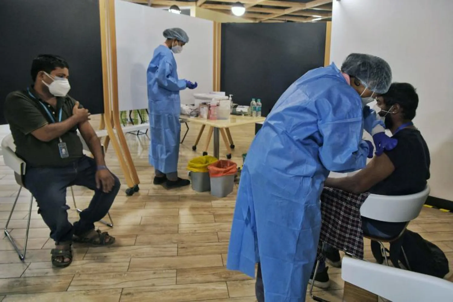 ممرض يقوم بتلقيح  بعض الموظفين في مبنى مكاتب «أمازون إنديا» في بنغالور (أ.ف.ب)