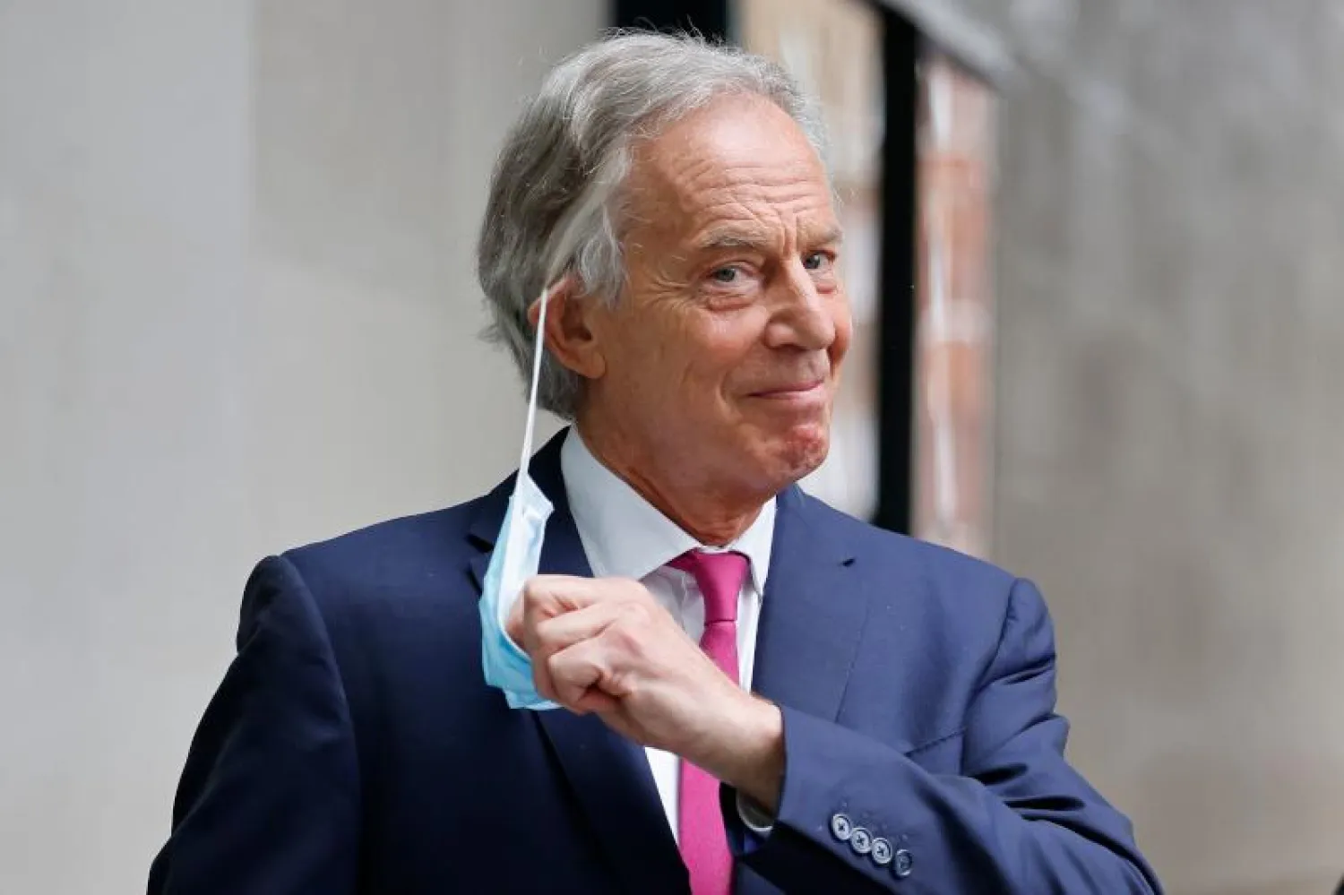 رئيس الوزراء البريطاني الأسبق توني بلير ينزع الكمامة من وجهه في لندن (أ.ف.ب)