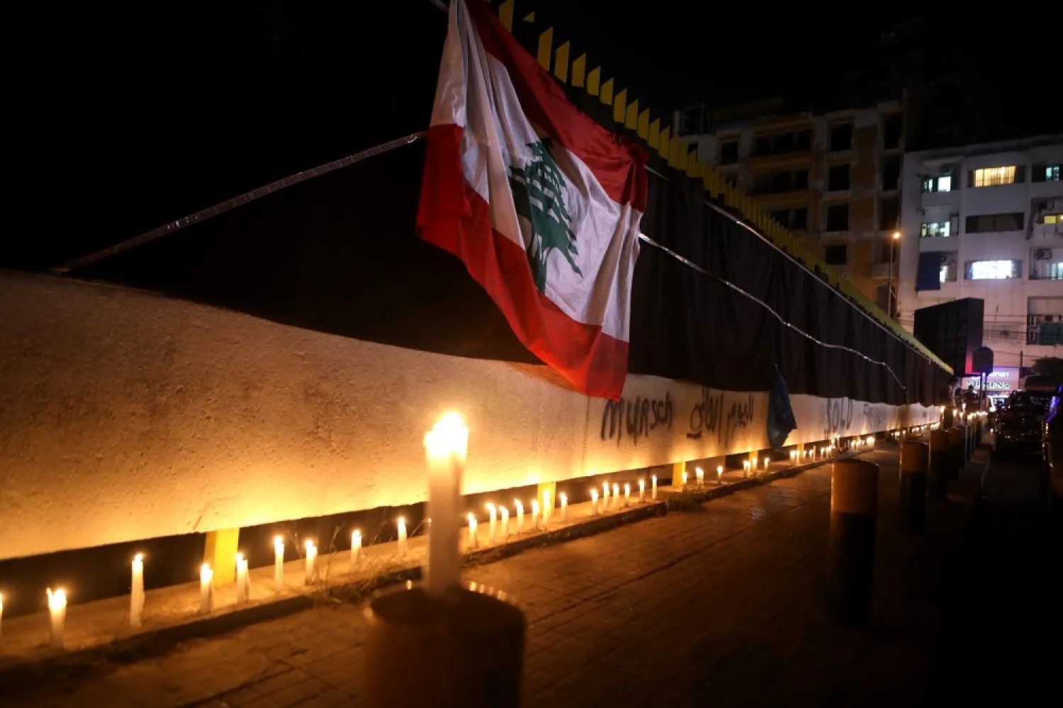 Lebanese flag hangs on the walls of the electricity company headquarters covered with black fabrics as protesters take part in a candlelight vigil in Beirut on November 11, 2020. (AFP)