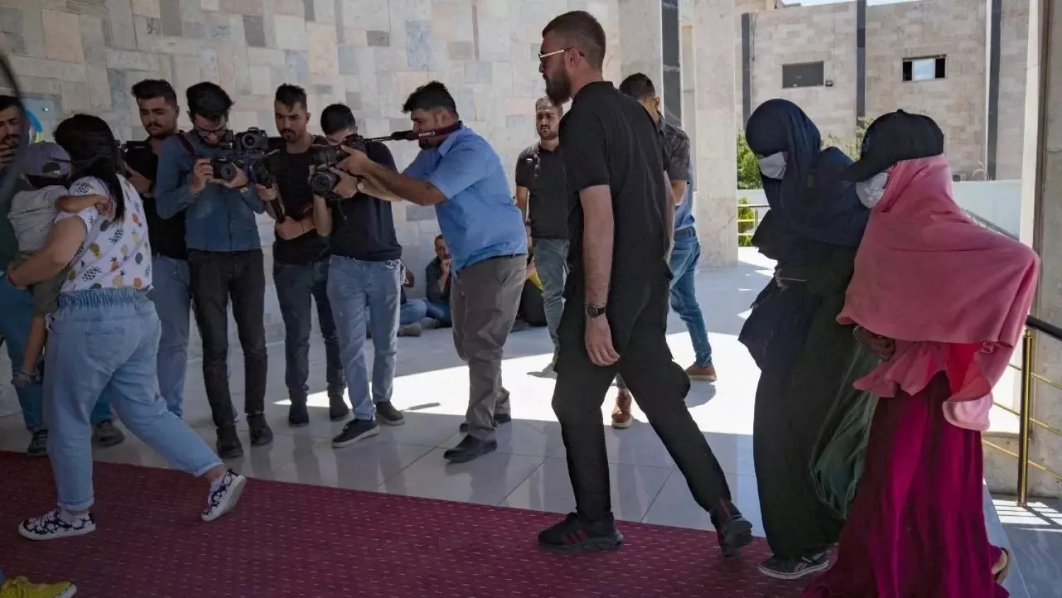 Members of Kurdish security forces accompany relatives of ISIS fighters before handing them over to a delegation of Dutch diplomats in Syria's northeastern city of Qamishli, on June 5, 2021. (AFP)
