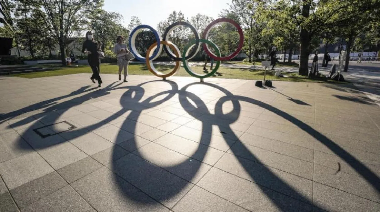 Ziyaretçiler, Tokyo’daki yeni ulusal stadyumun yakınındaki olimpiyat halkalarının yanından geçiyor (EPA)