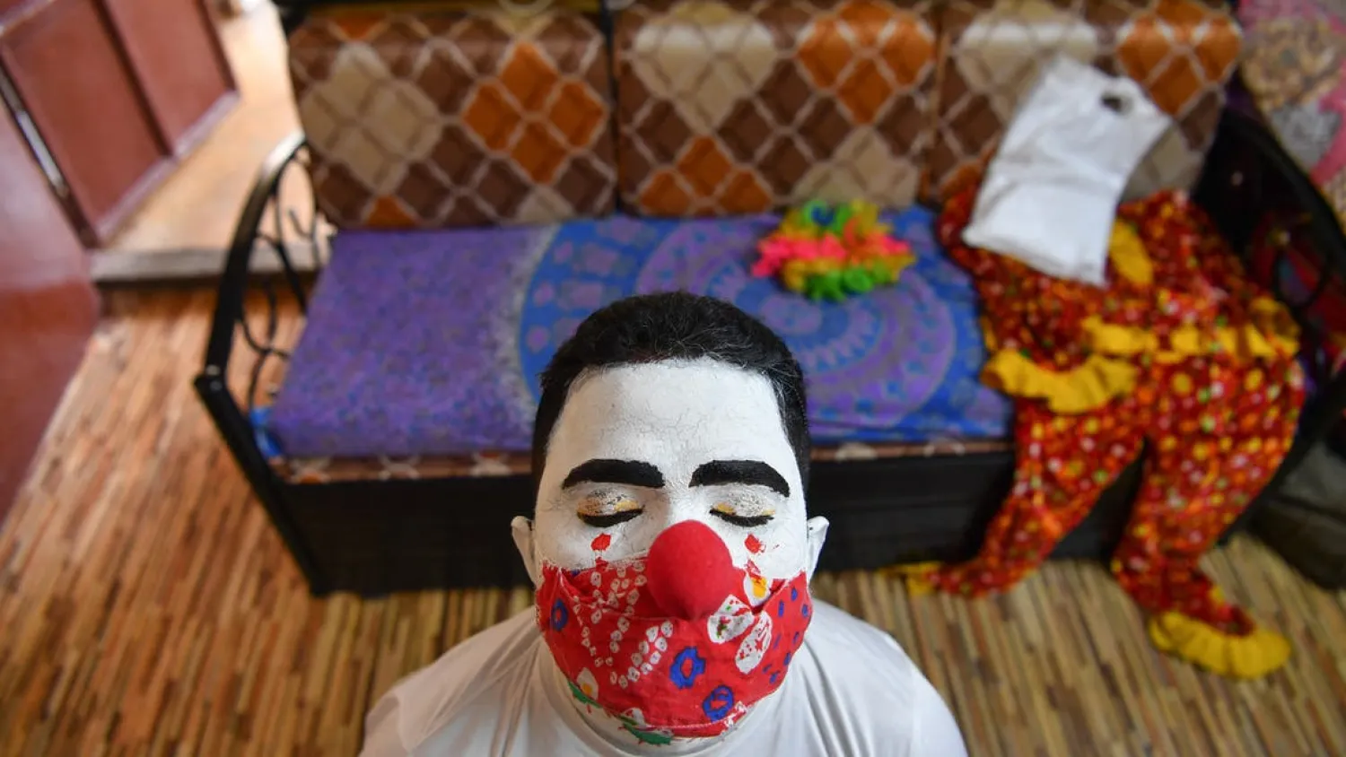 Social worker volunteer Ashok Kurmi, adjusts his clown nose
before going into slums to start a sanitation work and spread
awareness to follow the Covid-19 coronavirus safety protocols, at his
home in Mumbai on June 2, 2021. (File photo: AFP)