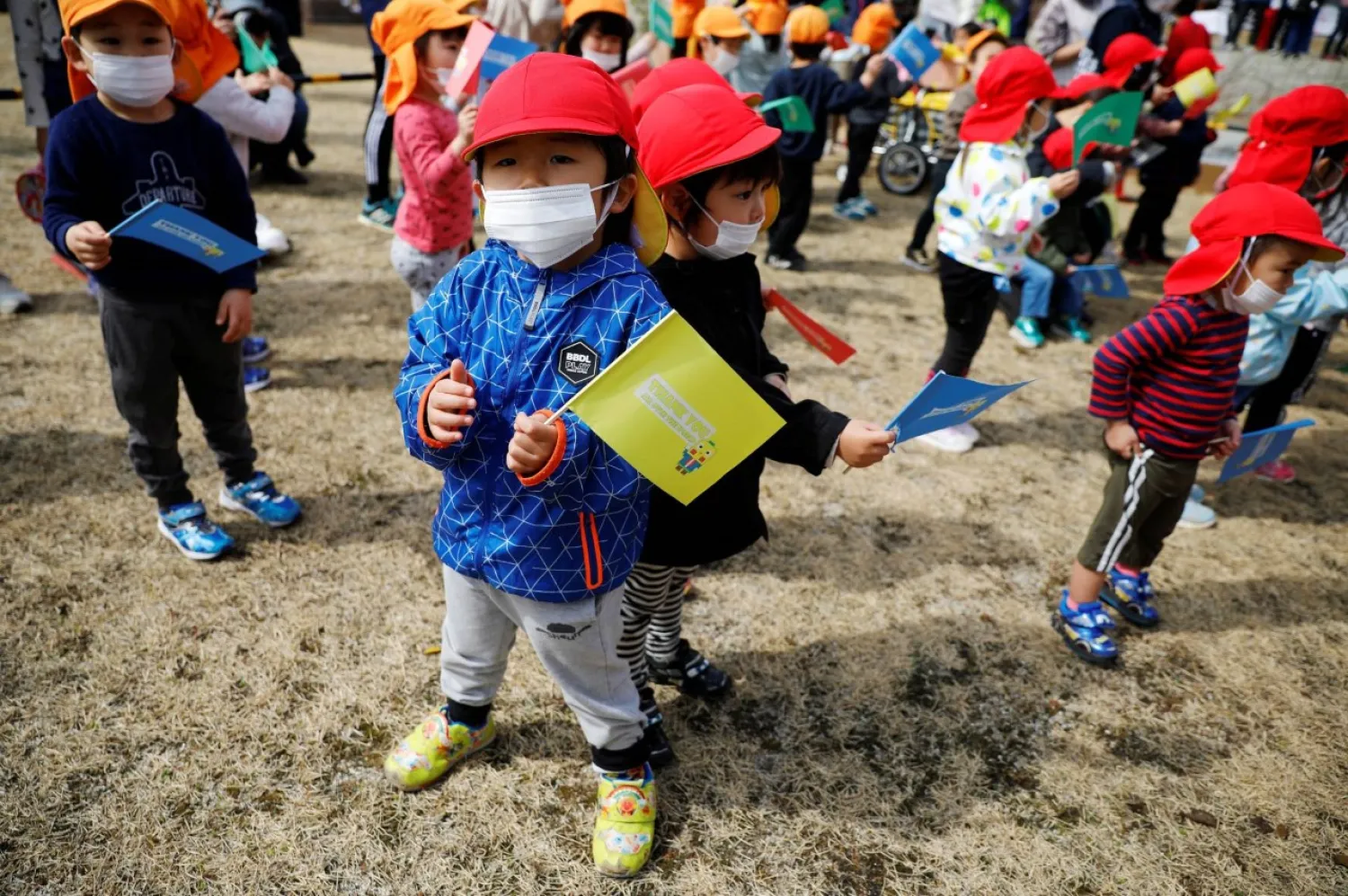 Children wait along the route of the Tokyo 2020 Olympic torch relay in the town of Naraha, Fukushima Prefecture, on March 25. Reuters