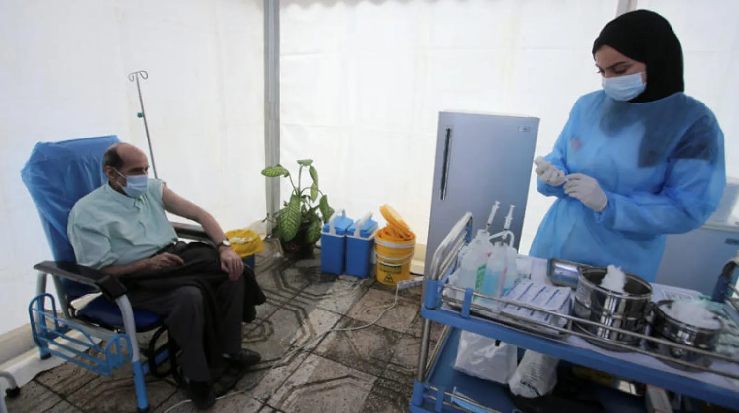 عاملة صحة تستعد لتلقيح مواطن جزائري في العاصمة الاثنين الماضي (رويترز)