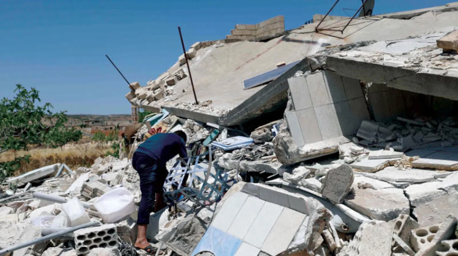 رجل يتفقد مبنىً مدمراً بعد قصف سوري وروسي جنوب إدلب أمس (أ.ف.ب)