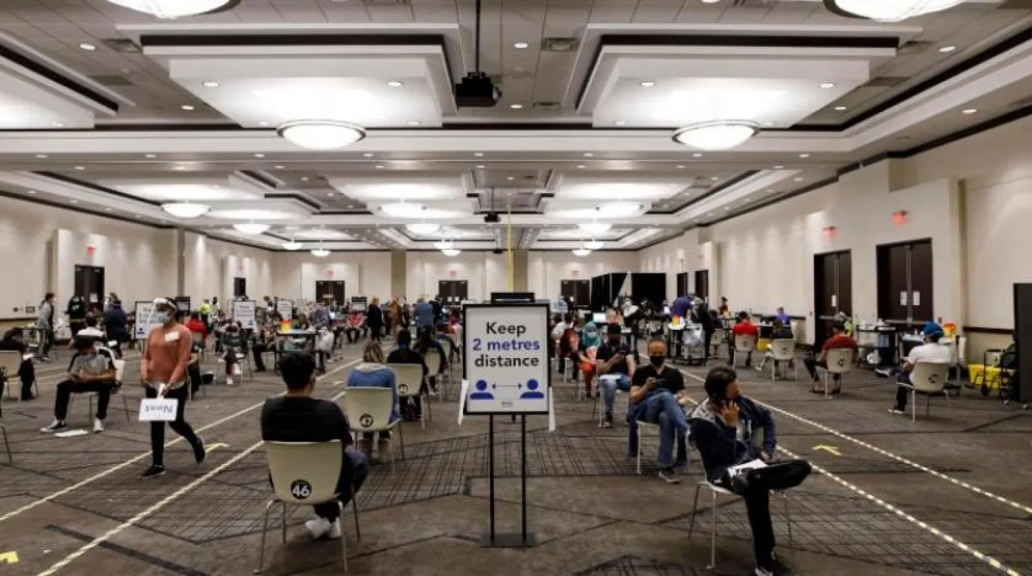 Ontario’daki Uluslararası Kongre Merkezi’nde aşı olmak için bekleyen insanlar (AFP)