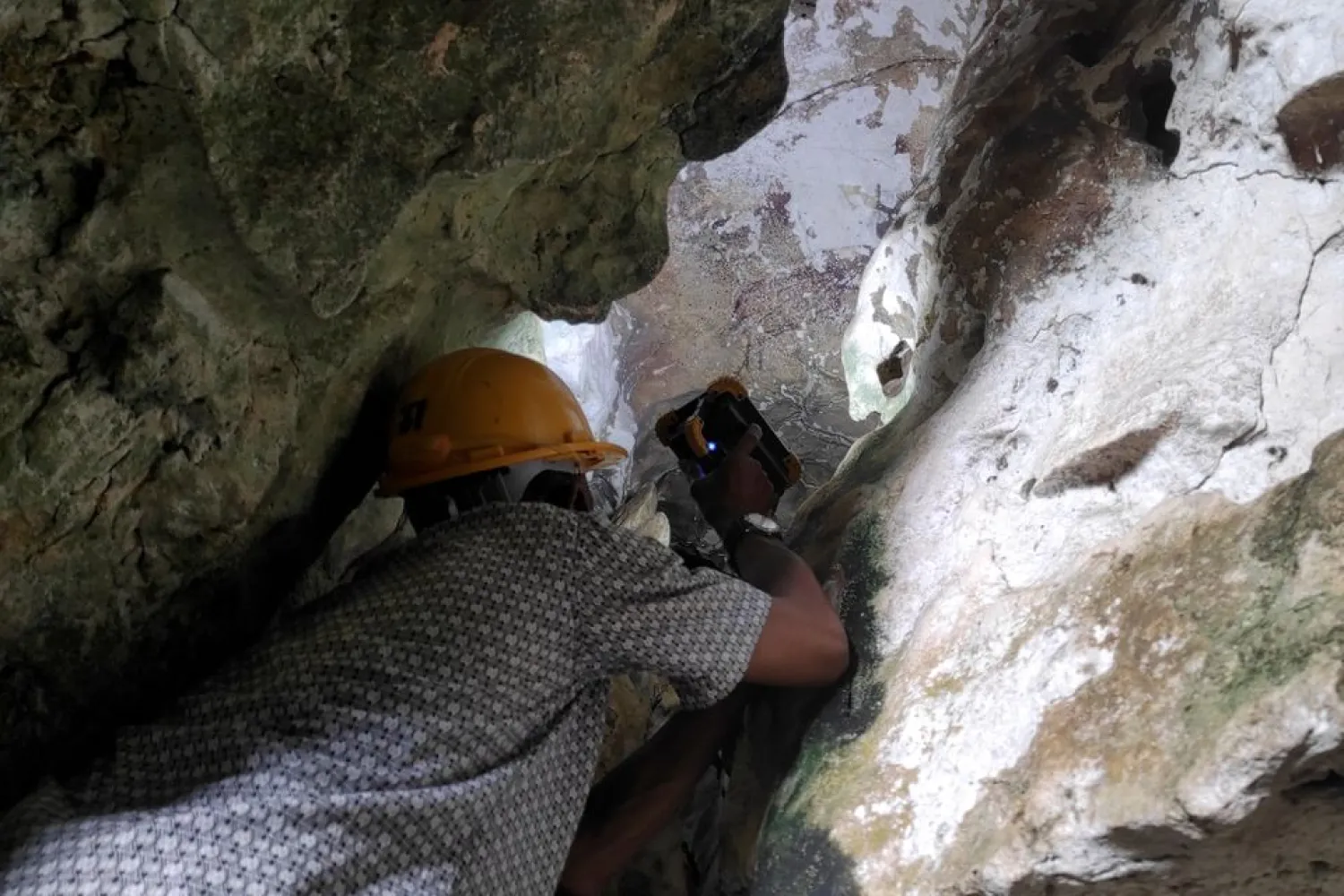 An archeologist using a torch inspects the world's oldest limestone cave painting, in Maros regency, South Sulawesi province, Indonesia, May 27, 2021. Picture taken May 27, 2021. (Reuters)