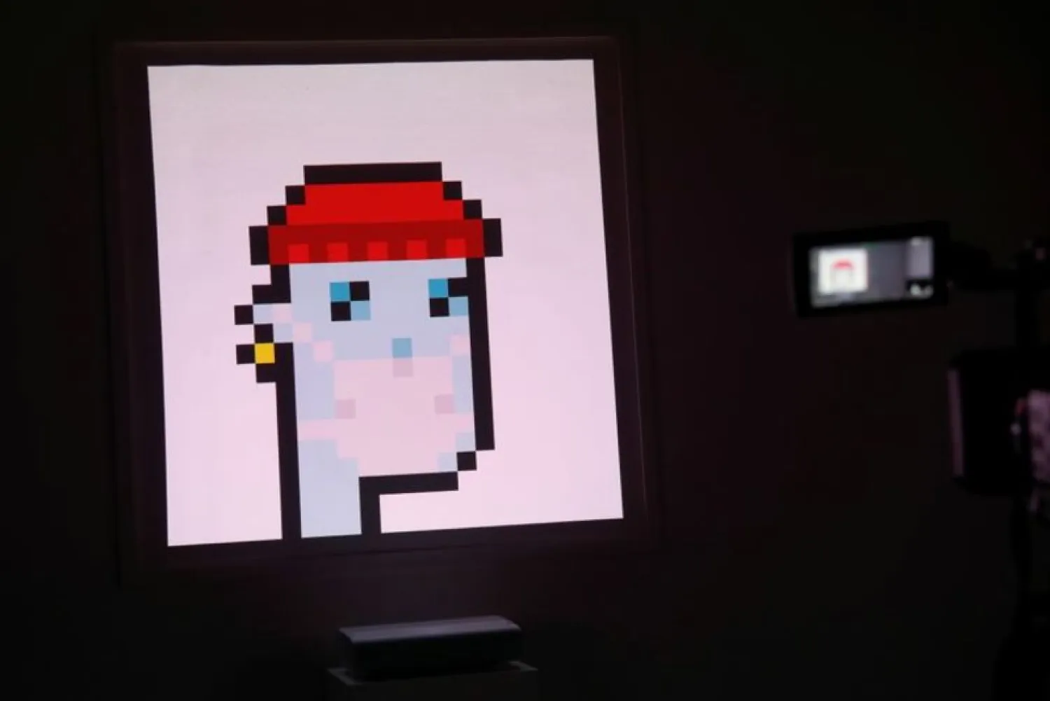 A television camera is seen next to the non-fungible token (NFT) “CryptoPunk #7523”, during a media preview for the “Natively Digital: A Curated NFT Sale” auction at Sotheby’s in New York City, US, June 4, 2021. (Reuters)