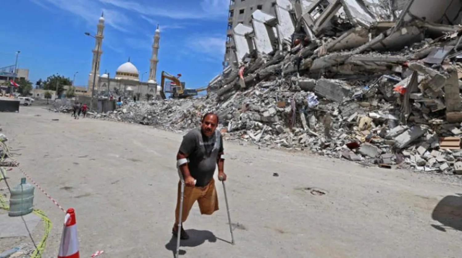 Gazze’de yıkılan binaların önünden koltuk değnekleriyle geçen bir Filistinli (AFP)