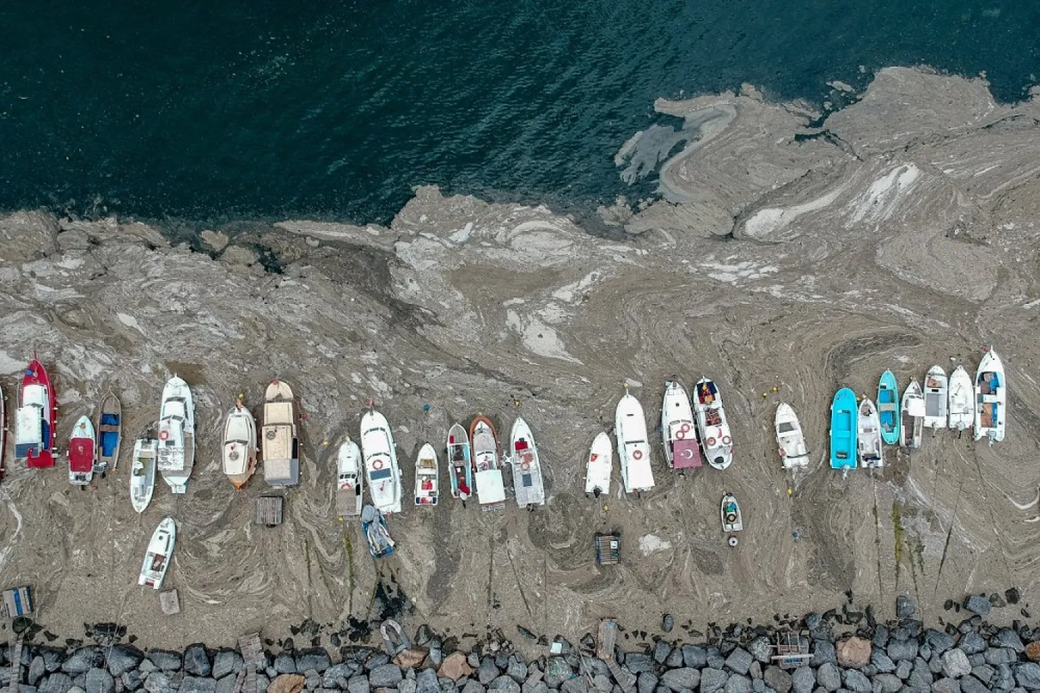 This aerial photograph taken on June 4, 2021, in Turkey's Marmara Sea at an Istanbul harbor shows mucilage, a jelly-like layer of slime that develops on the surface of the water due to the excessive proliferation of phytoplankton, gravely threatening the marine biome. (AFP)