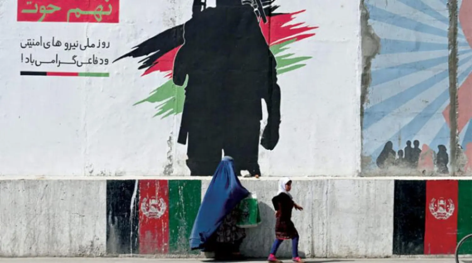 Afgan bir kadın ve kızı dün başkent Kabil'de bir askerin resmedildiği duvarın önünden geçerken (AFP)