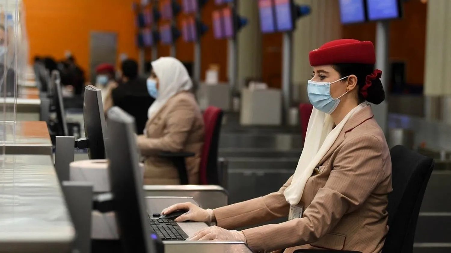 Ground hostesses of the Emirates airlines wear face masks and assist travellers fromp behind glass windows at Dubai International Airport on May 22, 2020, after the resumption of scheduled operations by the Emirati carrier, amid the ongoing novel coronavirus pandemic crisis. (File photo: AFP)
