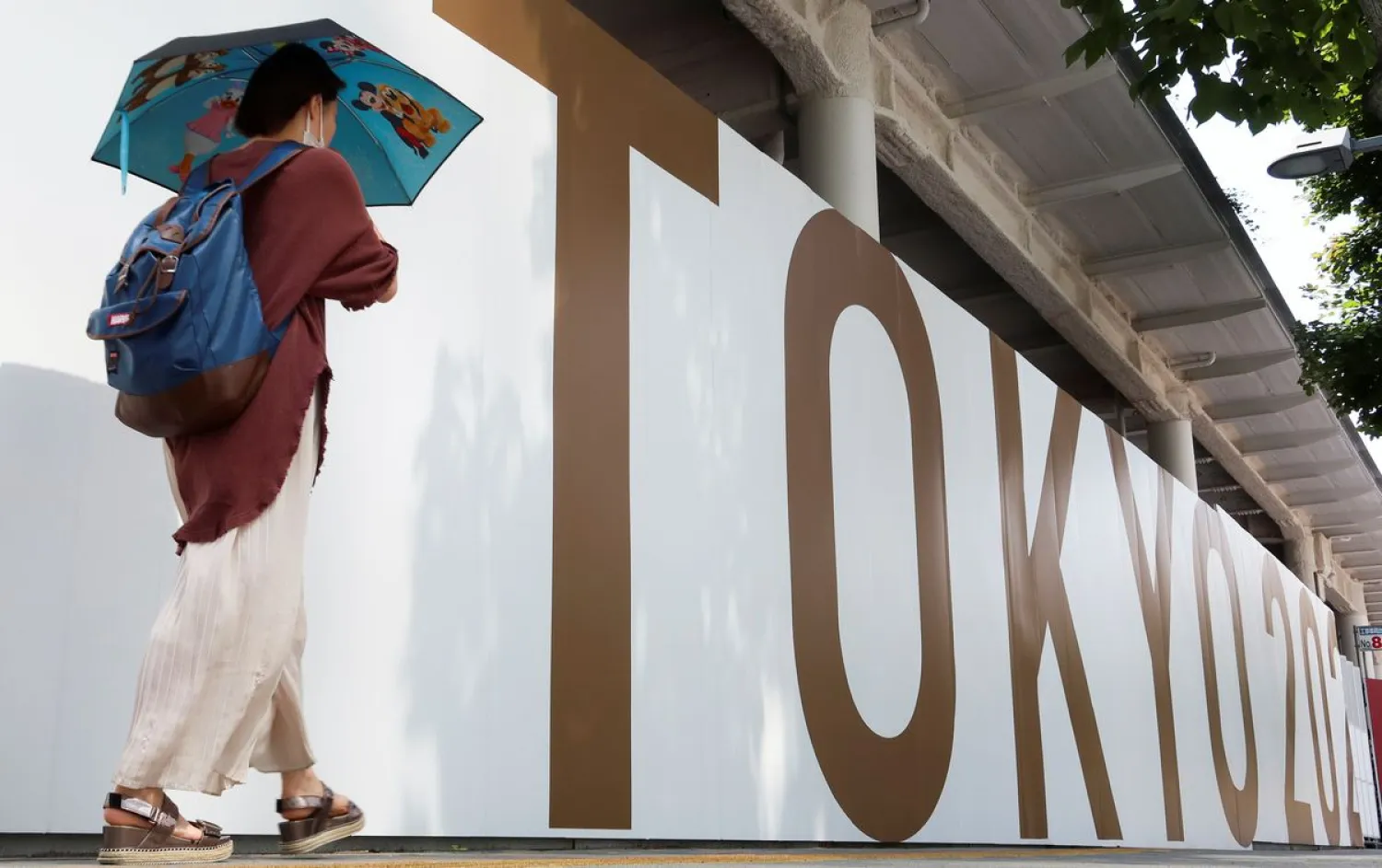 A woman walks outside the security fence of Olympic Stadium (National Stadium) built for Tokyo Olympic Games. Reuters