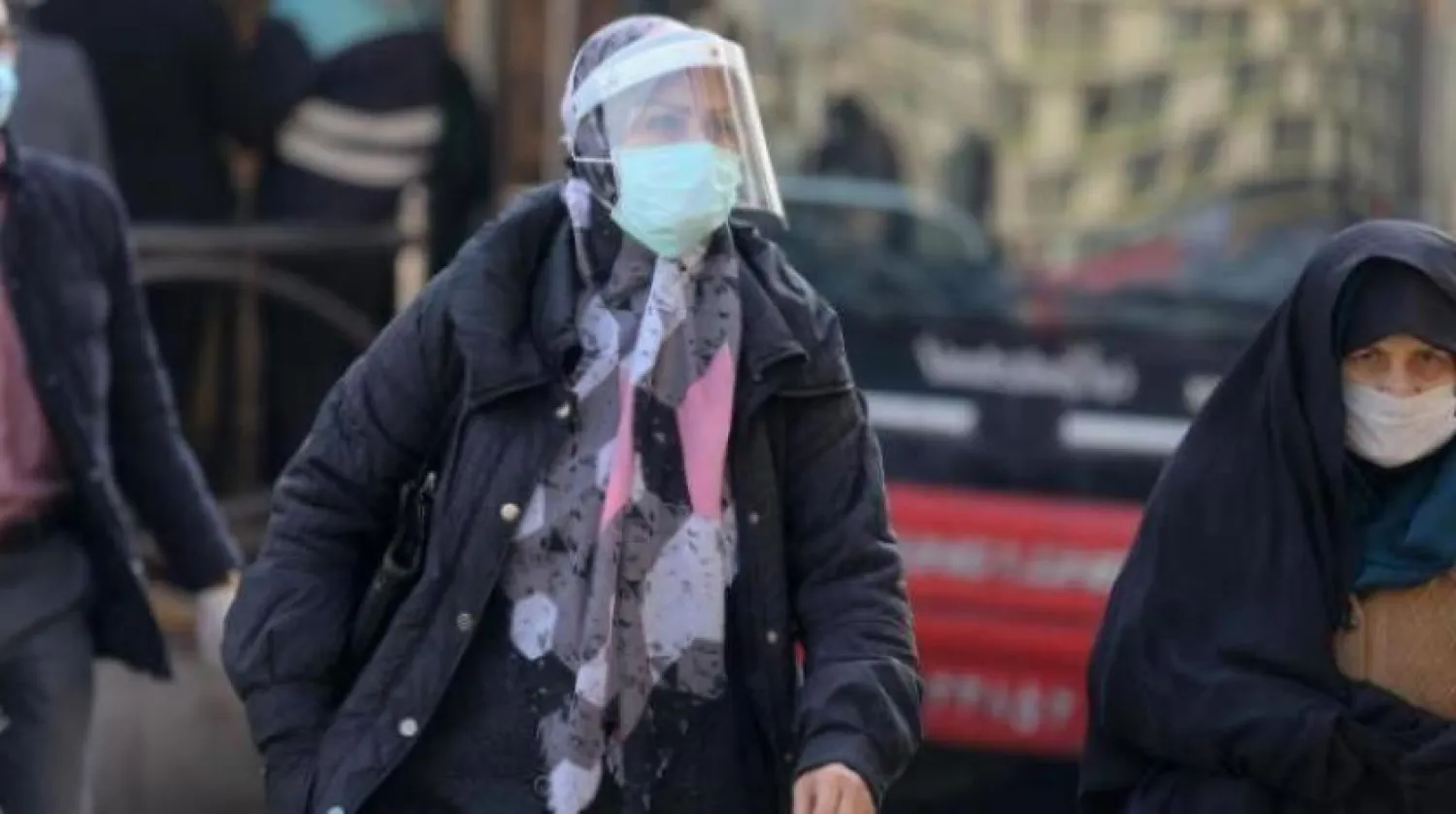 Tahran'da koronavirüsten korunmak için maske takan bir kadın (AFP)