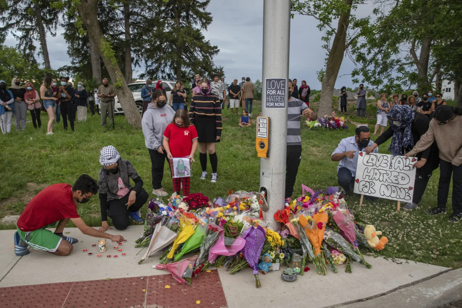 People attend a memorial at the location where a family of five was hit by a driver, in London, Ontario, June 7, 2021 (Brett Gundlock/The Canadian Press via AP)