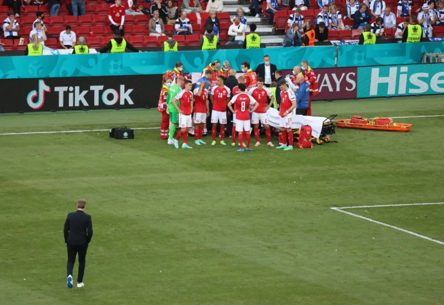 Denmark coach Kasper Hjulmand walks towards the Denmark players next to Christian Eriksen as he receives medical attention after collapsing during the match. (Reuters)