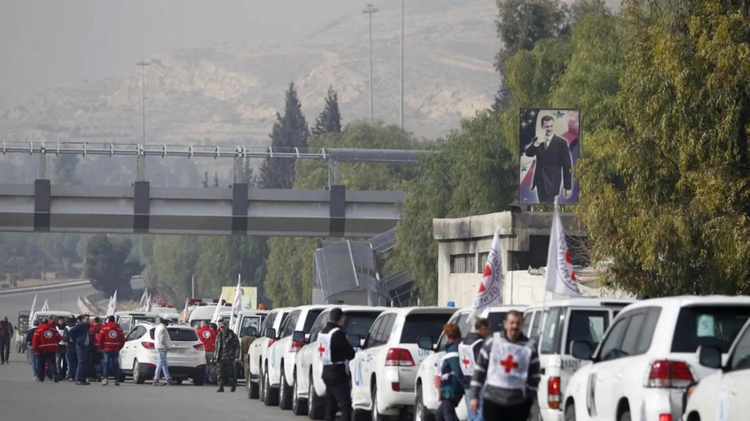 An aid convoy consisting of Red Cross, Red Crescent and UN vehicles comes together before delivering food and medical supplies in Syria. (Reuters)