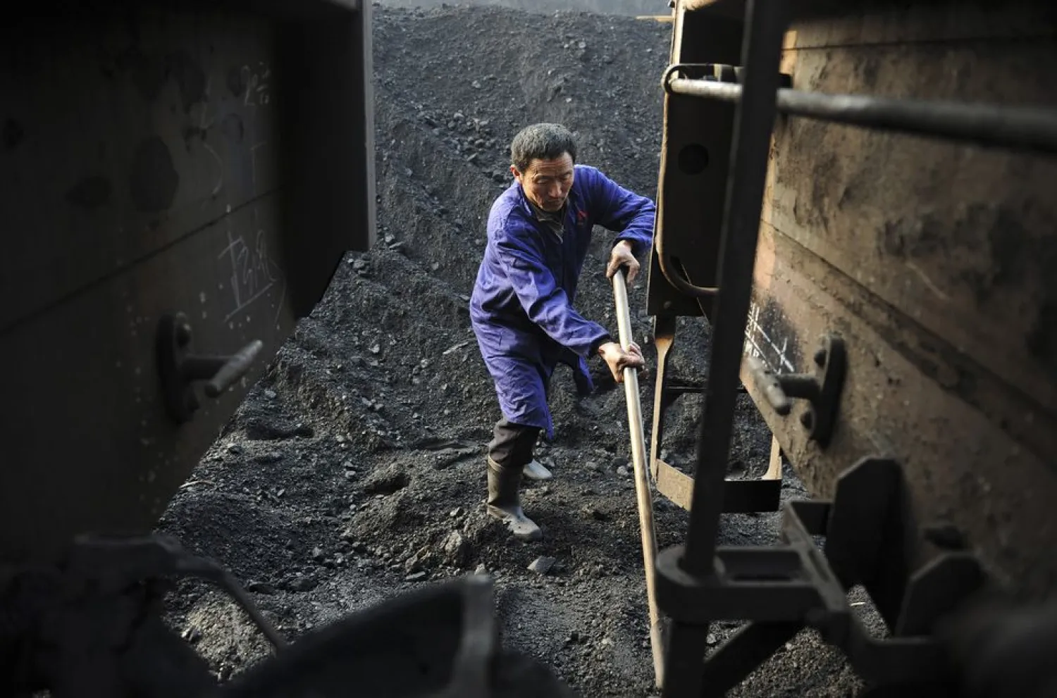 A worker shovels coal onto a freight train at a freight yard in Hefei, Anhui province, China, January 13, 2013. REUTERS/Stringer