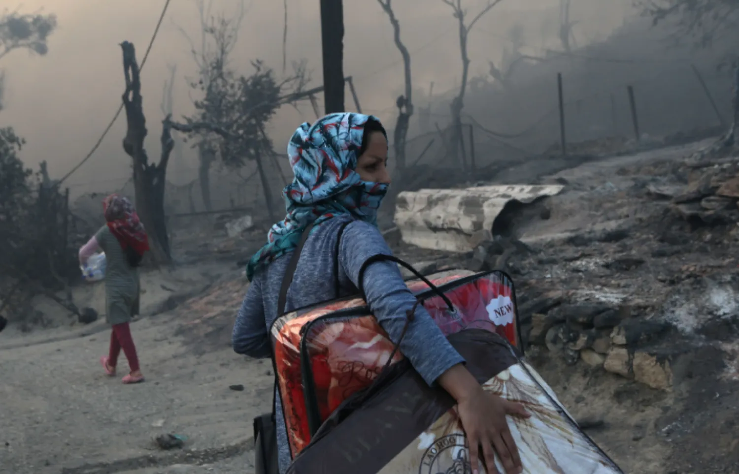 A migrant carries her belongings following a fire at the Moria camp for refugees and migrants on the island of Lesbos, Greece, Sept. 9, 2020. Reuters