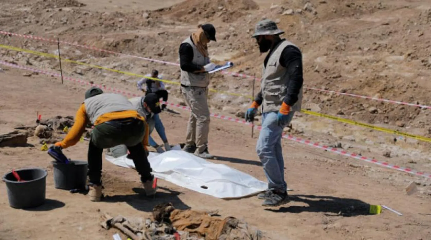 A team from the Iraqi Ministry of Health unearths the remains of a victim of the Badush prison massacre in the Nineveh governorate on Sunday. (Reuters)