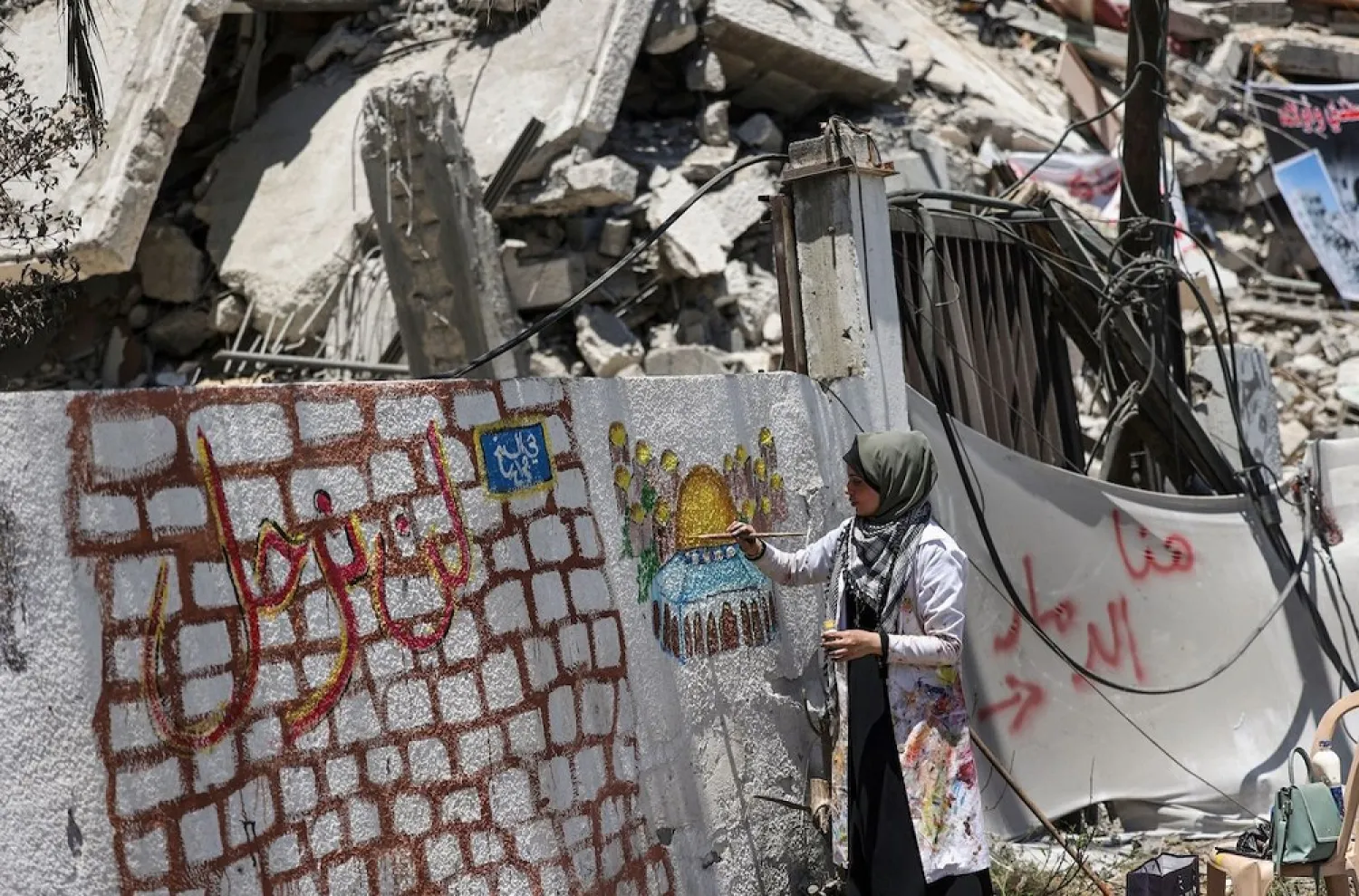 Palestinian artist Etaf al-Najili paints Al-Aqsa Mosque's Dome of the Rock in Jerusalem, on a remaining wall section of a damaged building in Gaza City, on May 24, 2021. (Getty Images)
