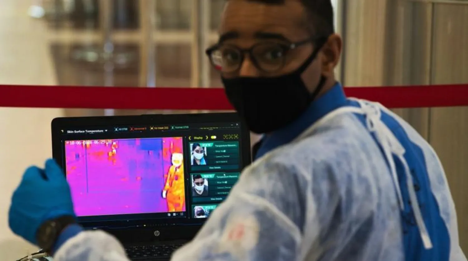 FILE - In this June 10, 2020 file photo, an official wearing a mask due to the coronavirus pandemic operates a temperature screening point at Dubai International Airport's Terminal 3 in Dubai, United Arab Emirates. (AP Photo/Jon Gambrell, File)
