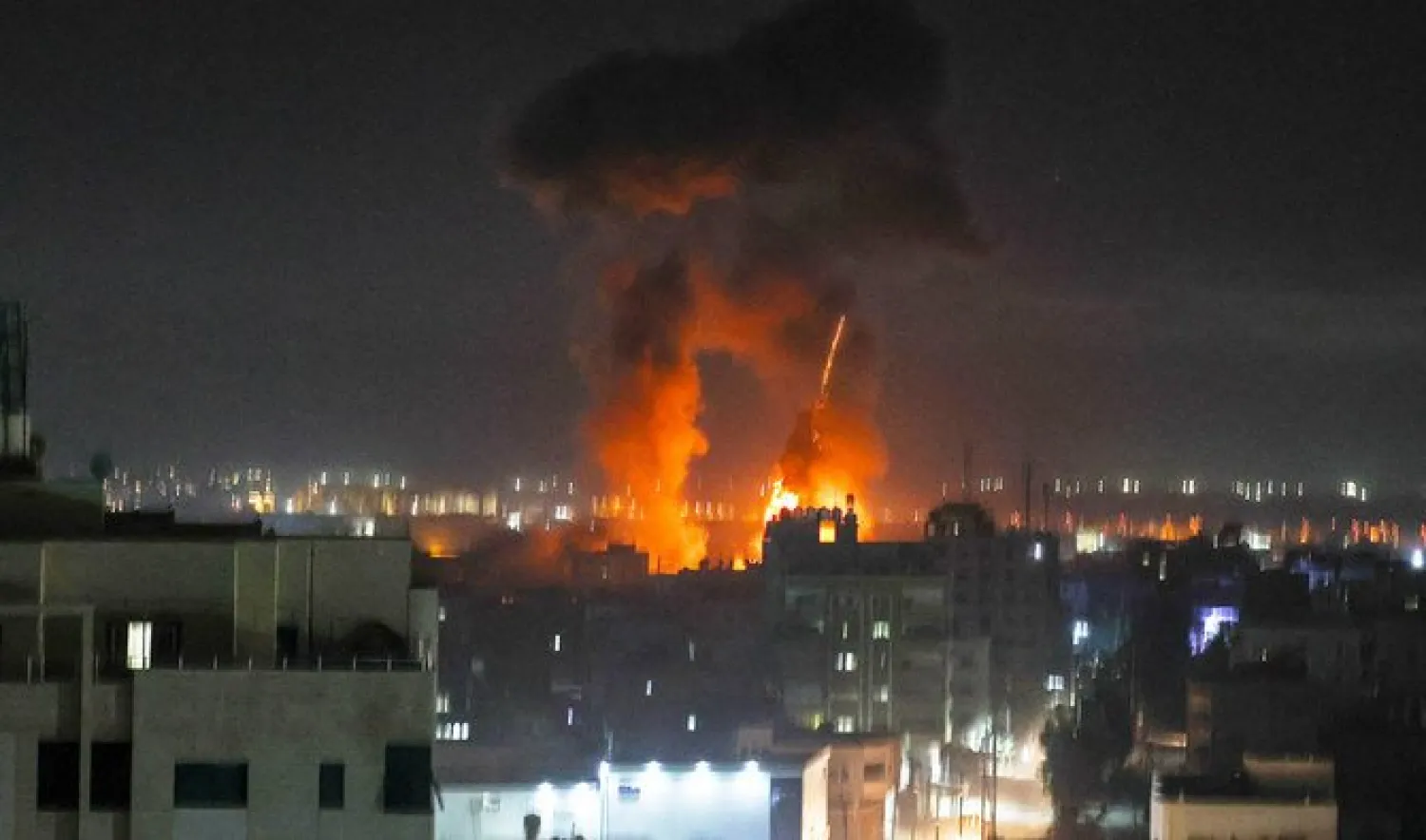 Explosions light-up the night sky above buildings in Gaza City as Israeli forces shell the Palestinian enclave, early on June 16, 2021. (AFP)
