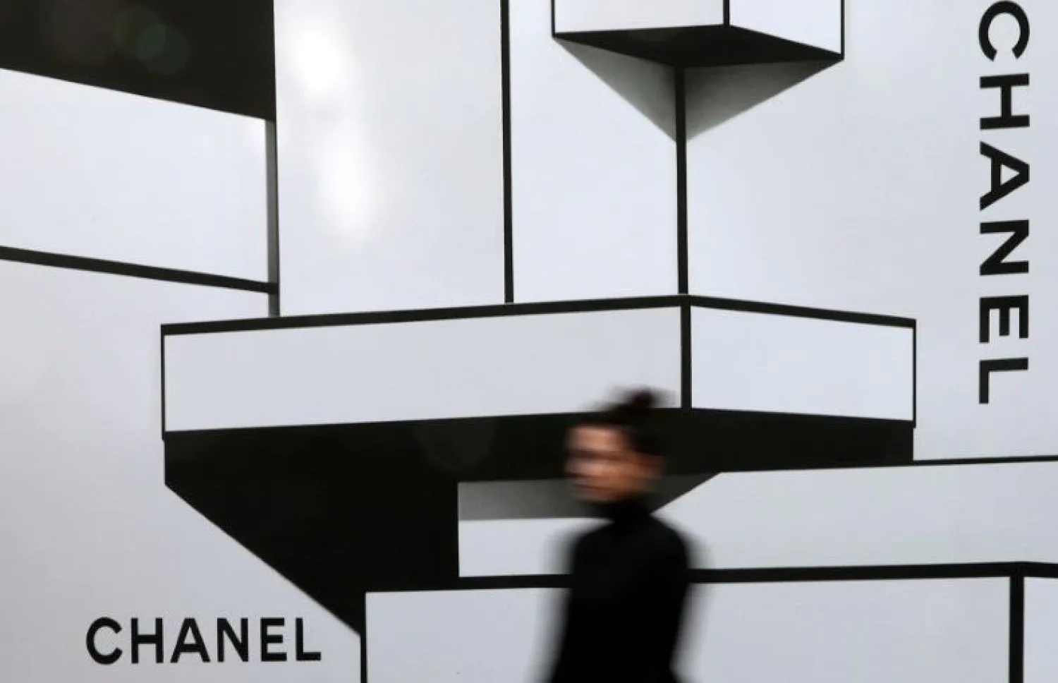 A woman walks past a wall with logos of French luxury goods maker Chanel in Nice, France, February 22, 2017. REUTERS/Eric Gaillard/File Photo



