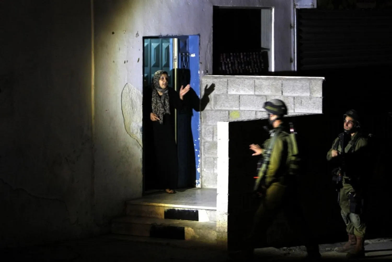 Israeli soldiers interrogate a Palestinian woman during a night raid in the occupied West Bank refugee camp of Jalazun, north of Ramallah, on June 16, 2014. (AFP)