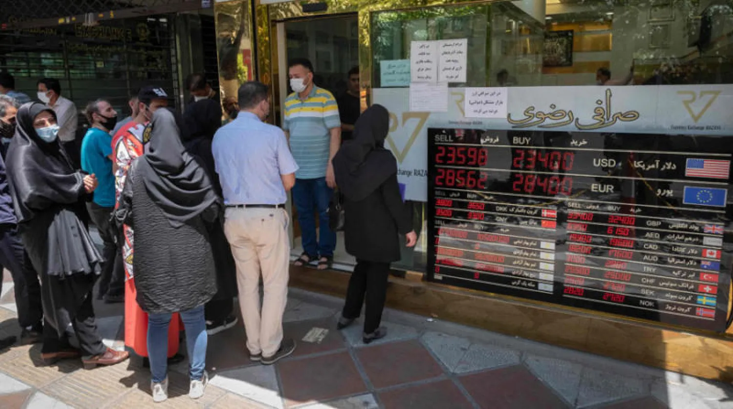 الإيرانيون يراقبون تطورات سوق العملة الأجنبية تحت تأثير الانتخابات الرئاسية أمام دار صرافة في طهران أول من أمس (أ.ف.ب)