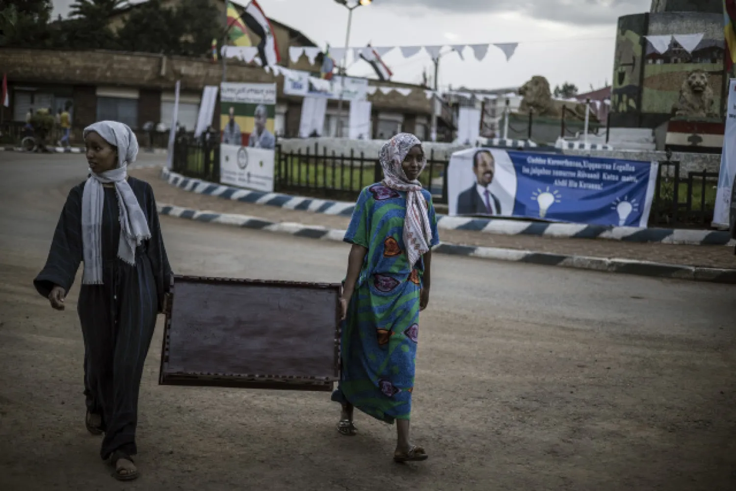 Women carry a coffee table at a traffic circle in Jimma, on June 15, 2021, on the eve of Ethiopian Prime Minister Abiy Ahmed's visit to the city during his electoral campaign ahead of June 21, 2021, vote. (MARCO LONGARI / AFP)
