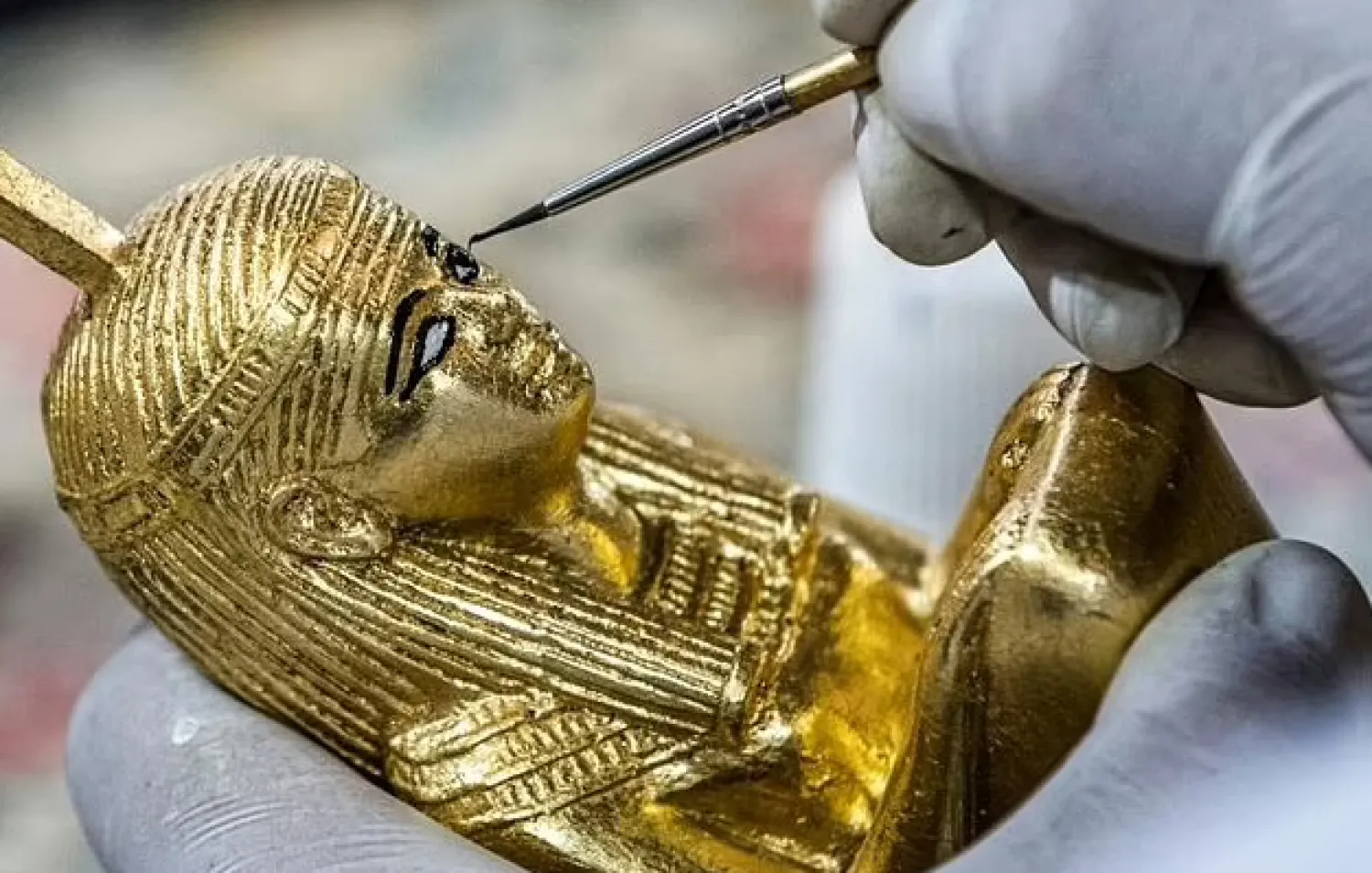 A technician paints a replica of an ancient Egyptian statue at the Konouz (Treasures) factory in Cairo - AFP