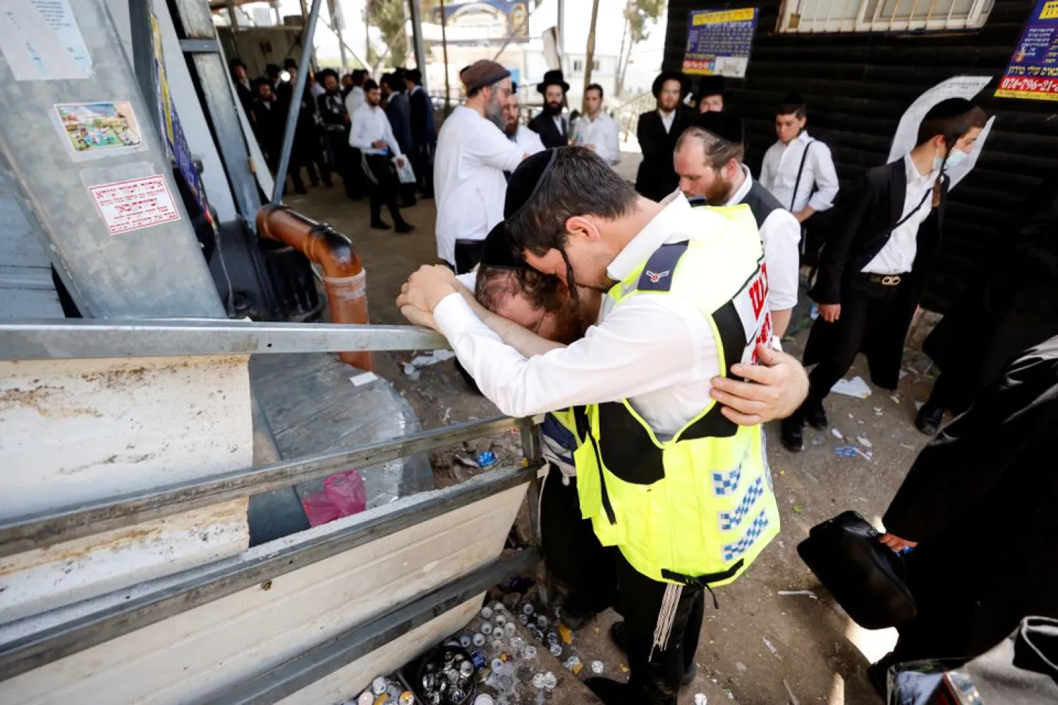 Emergency workers hug as they react at the site where dozens were crushed to death in a stampede at a religious festival, as the country observes a day of mourning, at Mount Meron, Israel May 2, 2021. REUTERS/Amir Cohen/File Photo


