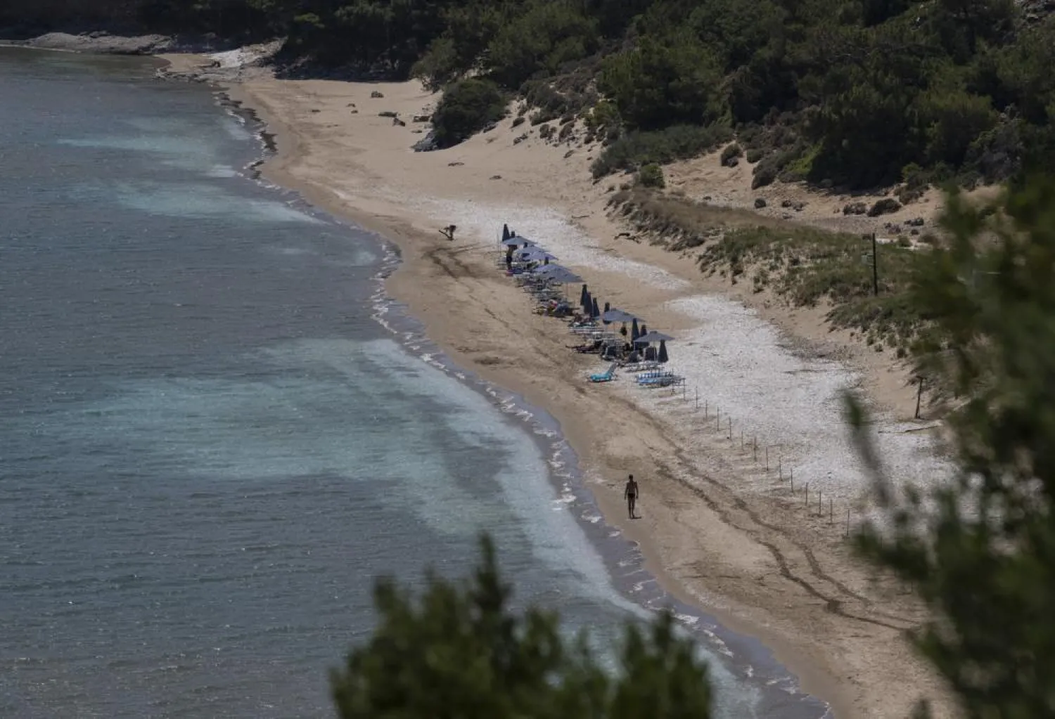 A man walks at the beach of Marathokampos, on the island of Samos, North Aegean, Greece, Wednesday June 9, 2021. (AP)
