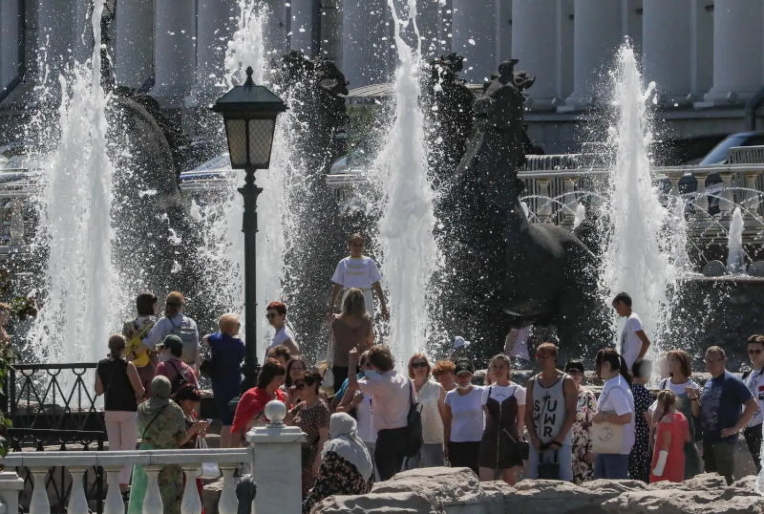 جمع من الناس عند إحدى نوافير موسكو هرباً من الحر ورغم تفشي الوباء مجدداً (إ.ب.أ)