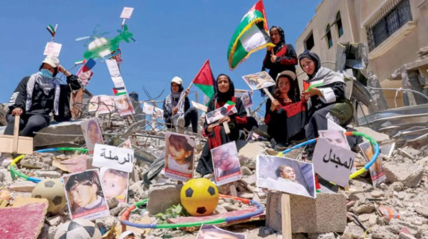 Han Yunus'taki Filistinliler, İsrail'in geçen ay Gazze'yi bombalaması sonucu hayatını kaybeden yakınlarının fotoğraflarını ve Filistin bayraklarını taşıdılar. (AFP)