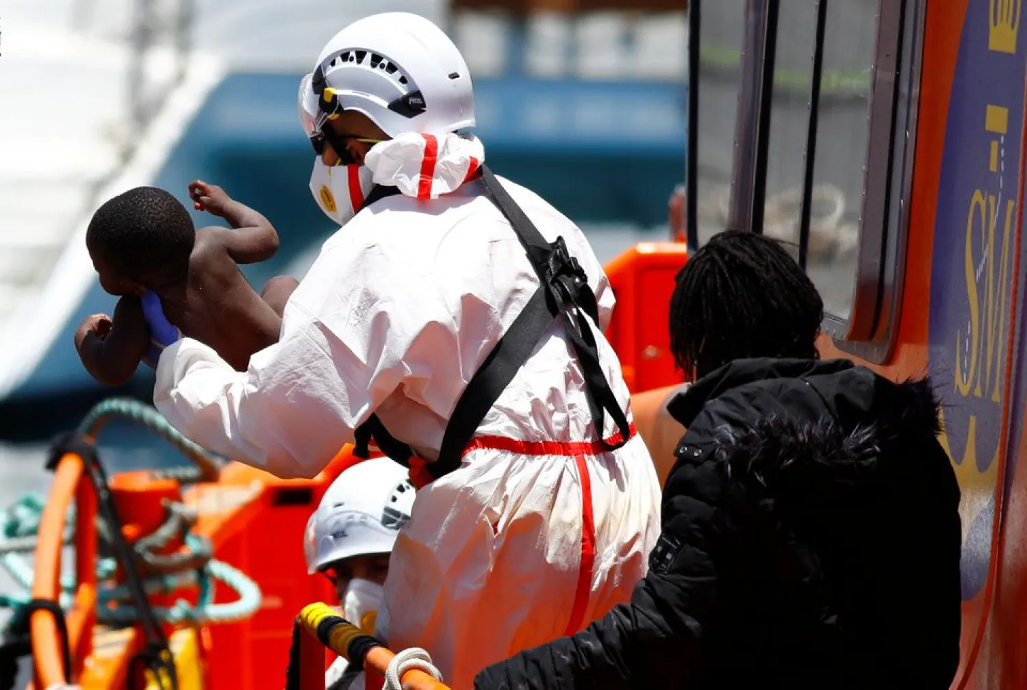 Rescuers help a migrant child to disembark from a Spanish coast guard vessel, in the port of Arguineguin, on the island of Gran Canaria, Spain June 20, 2021. REUTERS/Borja Suarez