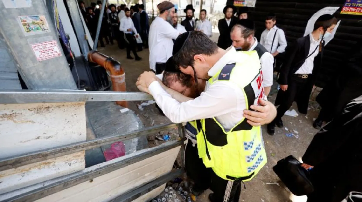 Emergency workers hug as they react at the site where dozens were crushed to death in a stampede at a religious festival, as the country observes a day of mourning, at Mount Meron, Israel May 2, 2021. REUTERS/Amir Cohen/File Photo
