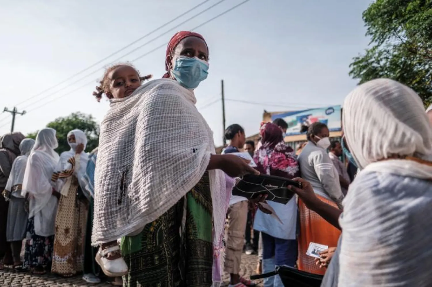 امرأة مع طفل تحمل بطاقة اقتراع بينما تنتظر في طابور للتصويت في مدينة بحر دار (أ.ف.ب)