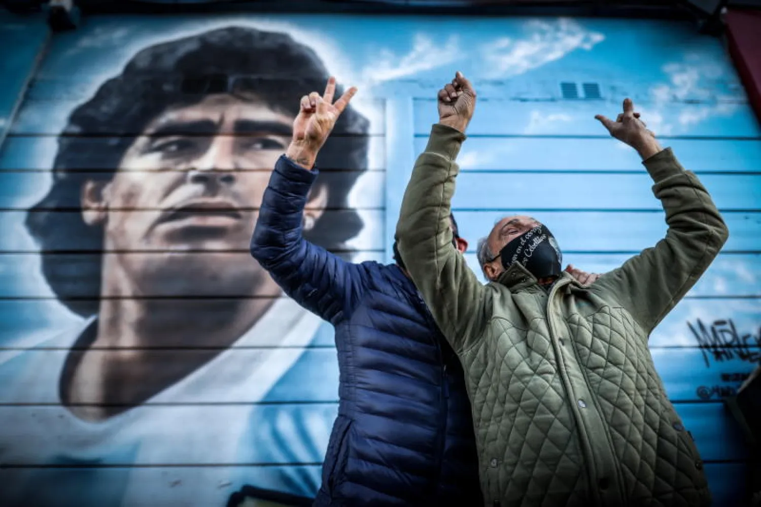 أرجنتينيون يحتفلون بهدف دييغو مارادونا أمام صورة له في بوينس أيرس (إ.ب.أ)