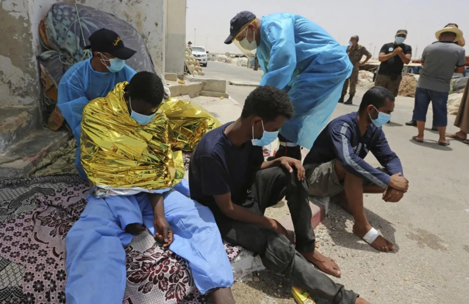 Migrants rescued by Tunisia's national guard during an attempted crossing of the Mediterranean by boat rest at the port of el-Ketef in Ben Guerdane in southern Tunisia near the border with Libya on June 27, 2021. (Photo by FATHI NASRI / AFP)