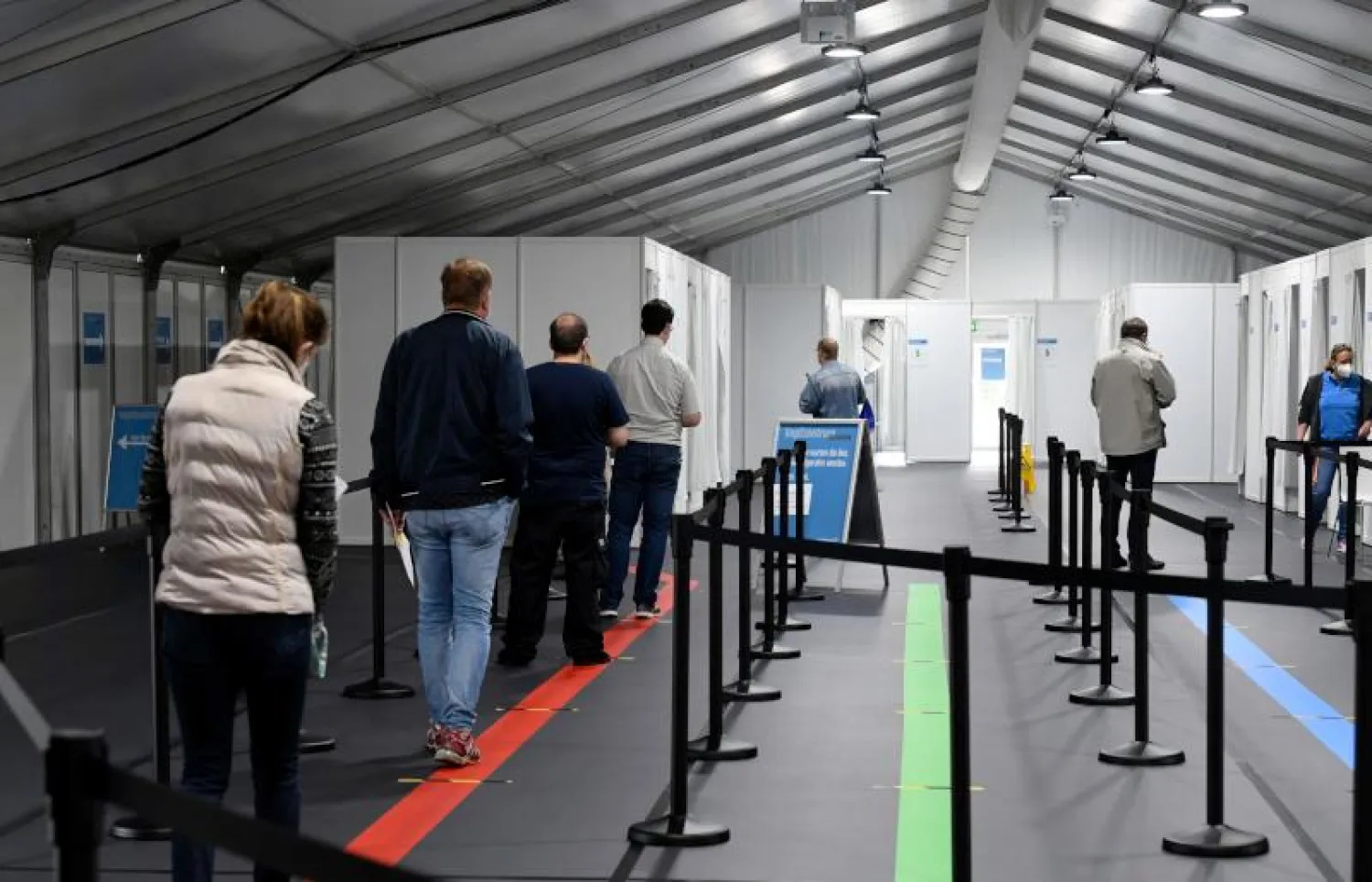 أشخاص يقفون في انتظار تلقي لقاح فايزر ضد فيروس كورونا في ليفركوزن غرب ألمانيا (أ.ف.ب)