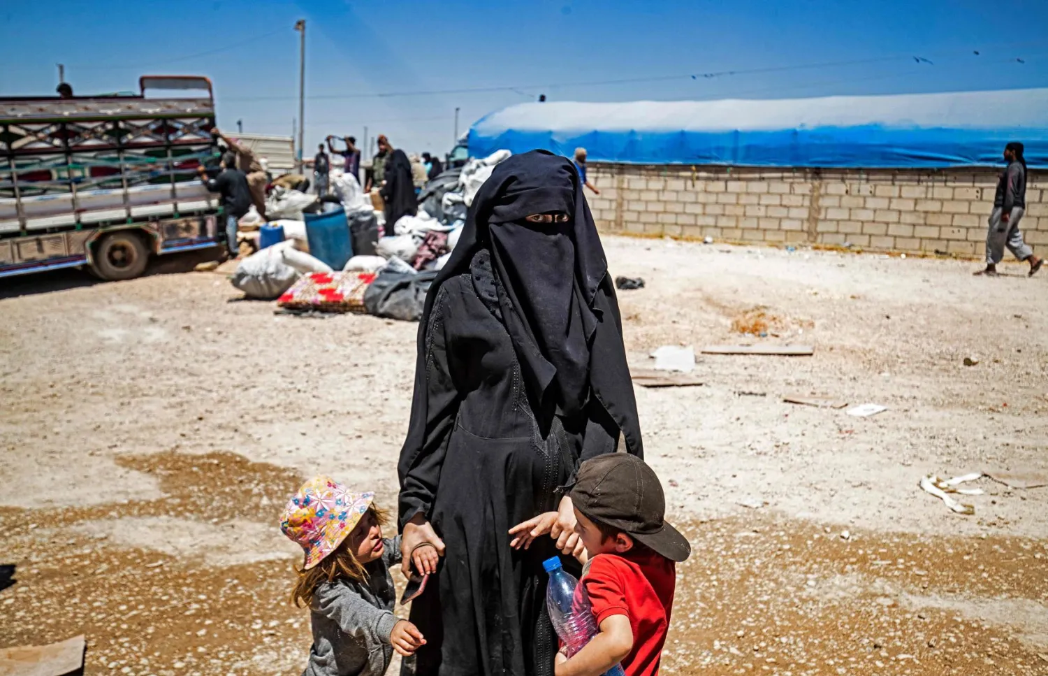 امرأة مع طفليها في مخيم الهول (أ.ف.ب)