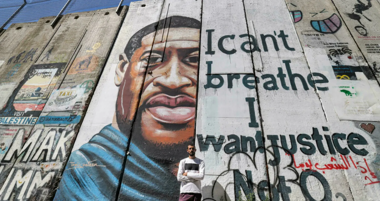Palestinian artist Taqi Spateen poses before his mural of African American George Floyd on Israel's barrier in the West Bank town of Bethlehem - AFP