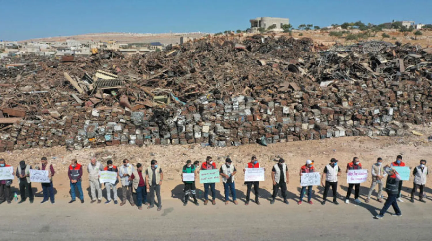 مشاركون في السلسلة البشرية المطالبة بإدخال المساعدات الإنسانية قرب معبر باب الهوى في إدلب أمس (أ.ف.ب)